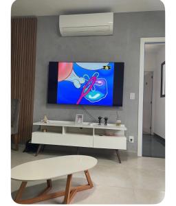 a living room with a tv on the wall at Apartamento Tranquilo e Aconchegante in Carmo do Rio Claro +6 photos