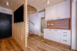 a kitchen with white cabinets and a flat screen tv at Cirus Riverfront Kolpa & Rafting in Kočevje