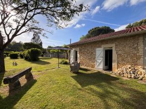 a stone house with a bench in the yard at Gîte Landes d armagnac in Roquefort