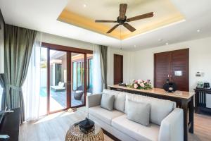 a living room with a couch and a ceiling fan at Triple Tree Beach Resort in Cha Am