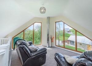 a living room with two leather chairs and large windows at Slate House Lodges in Llandinam