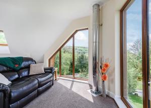 a living room with a leather couch and large windows at Slate House Lodges in Llandinam +51 photos