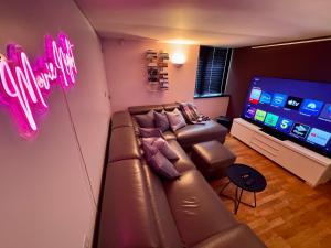 a living room with a leather couch and a flat screen tv at The Seahorse Torbay in Torquay