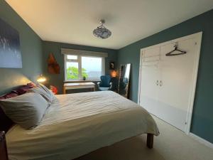 a bedroom with a white bed and a window at Mid-Century Gem Steps from the Beach in Edinburgh