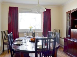 a dining room table and chairs with a table and a window at Tall Pines in Carrbridge