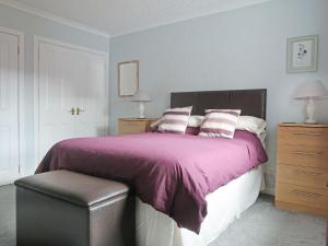 a bedroom with a bed with a purple blanket and a chair at Tall Pines in Carrbridge +11 photos