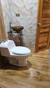 a bathroom with a white toilet and a sink at Pumaexplorer in Urubamba