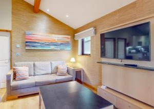 a living room with a couch and a large flat screen tv at Brockwood Hall Lodges in Silecroft