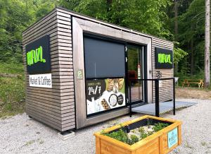 a small building with a large window and a pot of flowers at ECO River Camp - Pitches in Radovljica +28 photos