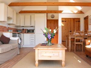 a living room and kitchen with a vase of flowers on a table at The Barn At Fishponds in Brook