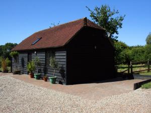 a black shed with potted plants in front of it at The Barn At Fishponds in Brook