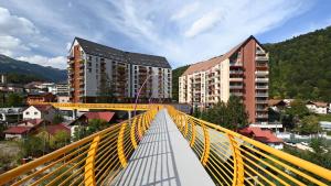 a yellow suspension bridge over a city with buildings at Hello Mountains Apartaments Sinaia in Sinaia