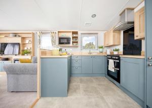 a kitchen with blue cabinets and a couch in it at Perran Heights Holiday Park in Perranzabuloe