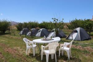 a white table and chairs with tents in the grass at Kol izem in Ksar el Kbir