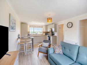a living room with a blue couch and a kitchen at Oaks - Uk47372 in Burgh le Marsh