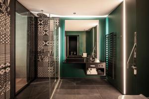 ein grünes Badezimmer mit Waschbecken und Spiegel in der Unterkunft Prinz Rudolf Smart Hotel in Meran