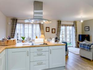 a kitchen with white cabinets and a sink and a living room at Popleys in Helmsley