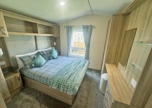a bedroom with a bed with blue pillows and a window at Aldbrough Leisure Park in Aldbrough