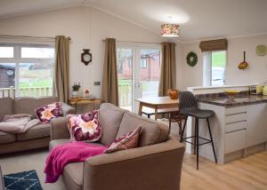 a living room with a couch and a table and a kitchen at Clear Sky Lodge Park in Kielder