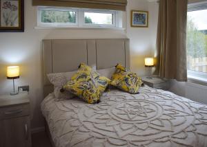 a bedroom with a bed with yellow pillows on it at Clear Sky Lodge Park in Kielder