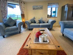 a living room with blue couches and a coffee table at Moor Farm Lodge in Bawdeswell