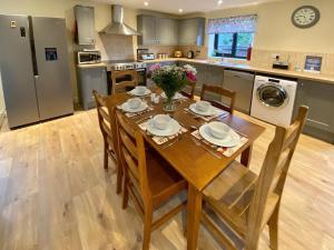 a kitchen with a wooden table with chairs and a dining room at Moor Farm Lodge in Bawdeswell
