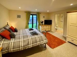 a bedroom with a bed and a television and a bathroom at Moor Farm Lodge in Bawdeswell +17 photos