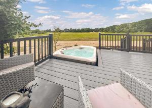 a hot tub on a wooden deck with two chairs at Watermill Leisure Park in Moortown