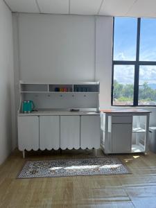 a kitchen with white cabinets and a large window at Tido Cottage in Macang