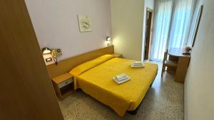 ein Hotelzimmer mit einem gelben Bett und einem Tisch in der Unterkunft Hotel Euromar in Rimini