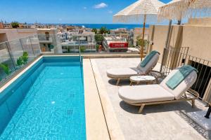 a swimming pool with two lounge chairs and an umbrella at Lemar Luxury Apartments in Hersonissos