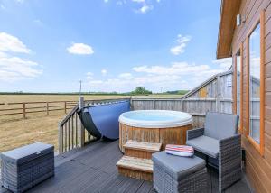 a deck with a hot tub and a table and chairs at Larkrise Farm Lodges in Babcary