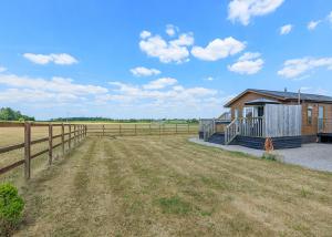 a house with a fence next to a field at Larkrise Farm Lodges in Babcary