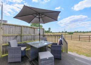 a table and chairs with an umbrella on a deck at Larkrise Farm Lodges in Babcary
