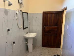 a bathroom with a sink and a mirror and a door at Leaf Villa in Arugam Bay
