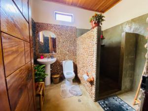 a bathroom with a toilet and a sink and a mirror at Monte Mar SãoTomé in M. Peixe