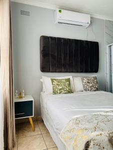 a bedroom with a bed with a black headboard at Kim Guesthouse in Harare