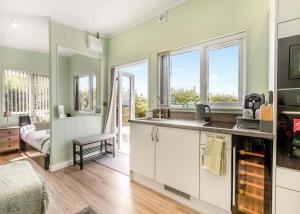 a kitchen with green walls and white cabinets and windows at Calvesland Hideaway in Manorbier