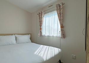 a bedroom with a bed and a window with curtains at The Chase Holiday Park in Addlethorpe