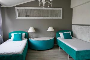 two beds in a room with blue chairs and a table at Brio boutique hotel in Velingrad