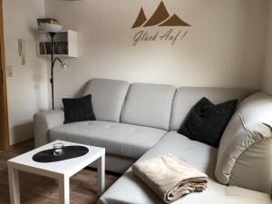 a living room with a white couch and a table at Schlupfwinkel Mohnen Mit E-Ladestation in Clausthal-Zellerfeld