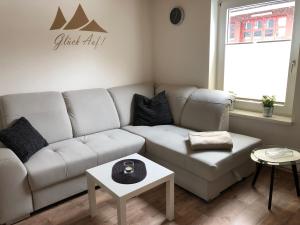 a living room with a white couch and a table at Schlupfwinkel Mohnen Mit E-Ladestation in Clausthal-Zellerfeld