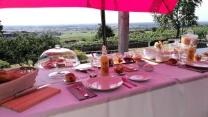 a pink table with plates and glasses and an umbrella at Petite chambre confortable vignoble bourguignon in Brochon +12 photos