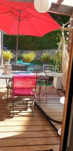 a table with a red umbrella on a wooden deck at Petite chambre confortable vignoble bourguignon in Brochon