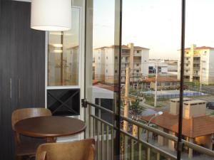 balcón con mesa, sillas y vistas a la ciudad en Apartamento Aeroporto, en Porto Alegre