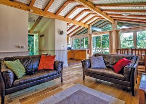 two leather couches in a living room with windows at Great Wood Lodges in Flaxton +14 photos
