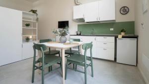 a kitchen with a white table and green chairs at Casa del Falegname - Loft Rovere con cucina in San Giovanni in Bosco +2 photos