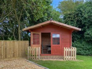 a red shed in a yard with a fence at Ivy - Uk47373 in Burgh le Marsh