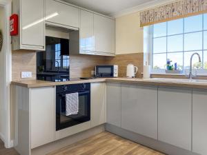 a kitchen with white cabinets and a stove top oven at Ivy - Uk47373 in Burgh le Marsh