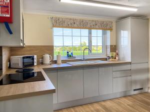 a kitchen with white cabinets and a sink and a window at Ivy - Uk47373 in Burgh le Marsh +4 photos